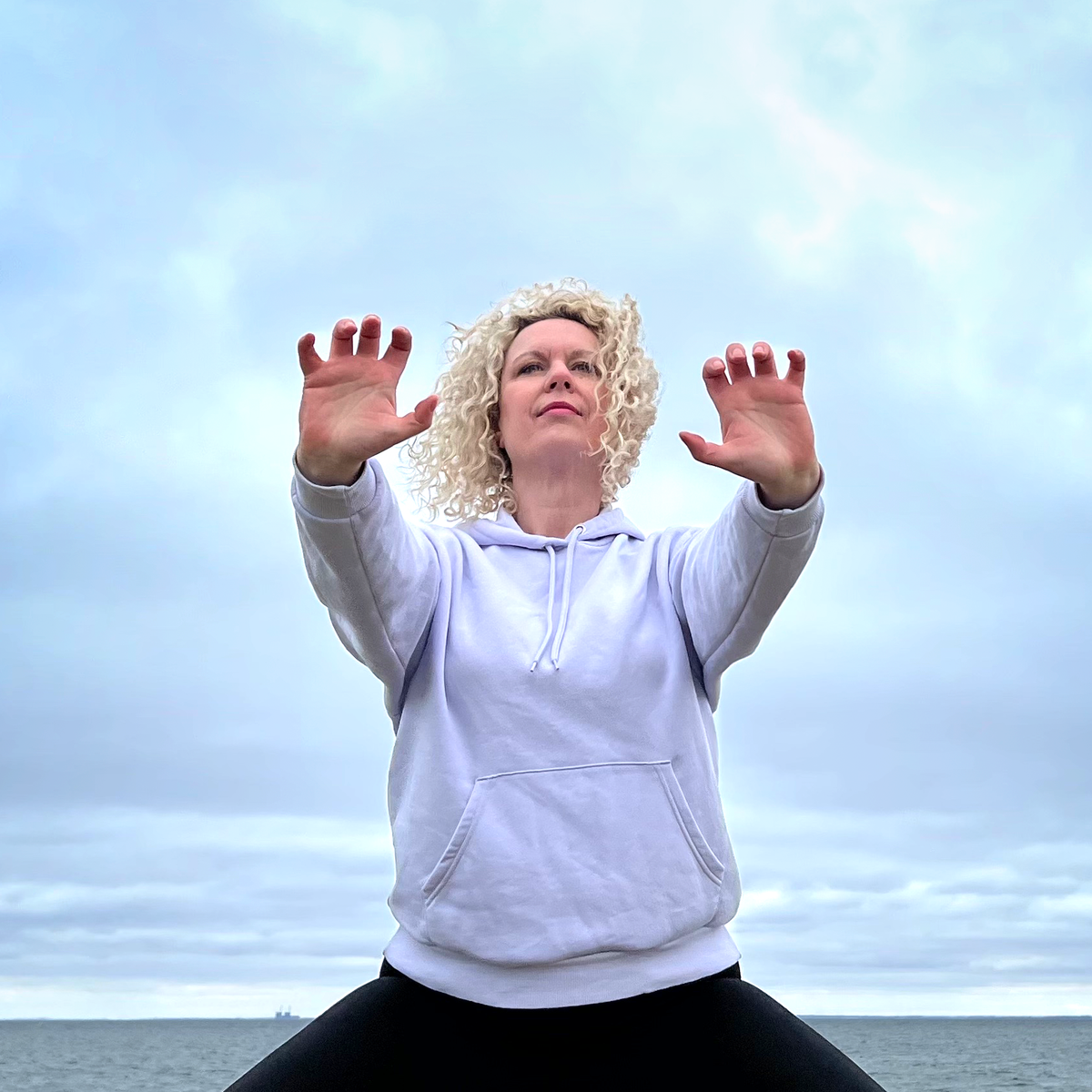 Sanna Fo utövar qigong med händerna lyfta mot himlen